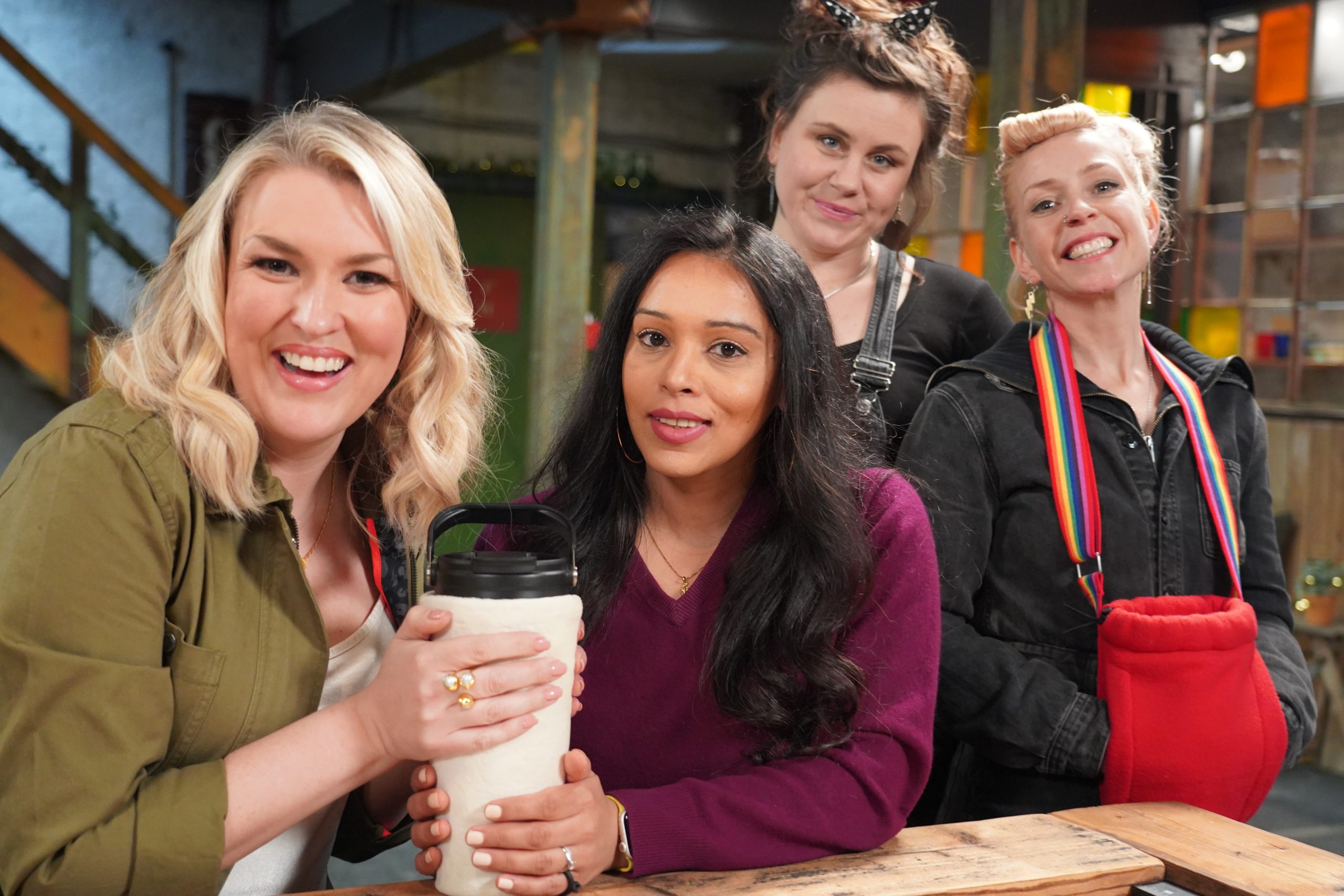2 ladies holding an invention with 2 ladies looking on